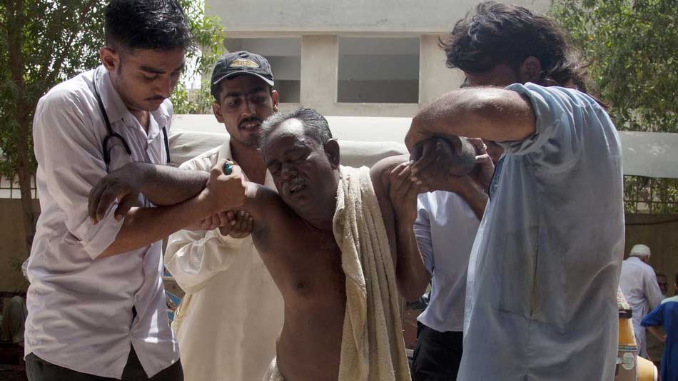 People rush a patient to a hospital suffering from heatstroke in Karachi, Pakistan, Tuesday, June 23, 2015. A scorching heat wave across southern Pakistan's city of Karachi has killed more than 400 people, authorities said Tuesday, as morgues overflowed with the dead and overwhelmed hospitals struggled to aid those clinging to life. (AP Photo/Shakil Adil)