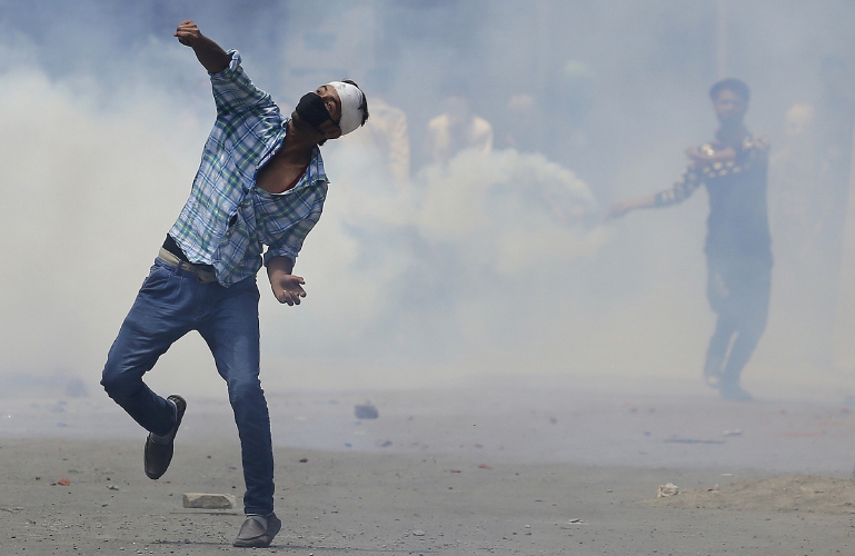 Kashmiri Muslim protesters throw stones at Indian paramilitary soldiers in Srinagar, Indian controlled Kashmir, Sunday, July 10, 2016. Indian troops and protesters clashed in several parts of the state despite a curfew imposed in the Himalayan region following the killing of a popular rebel commander. (AP Photo/Mukhtar Khan)